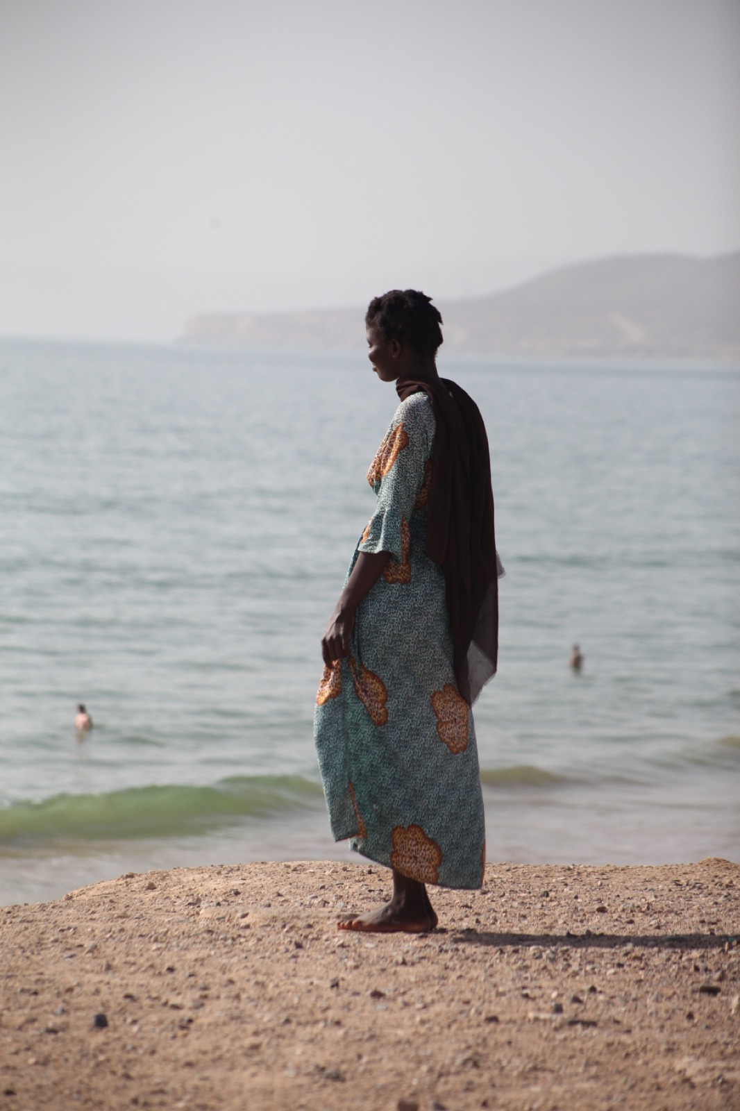 A person in patterned clothing standing by the water